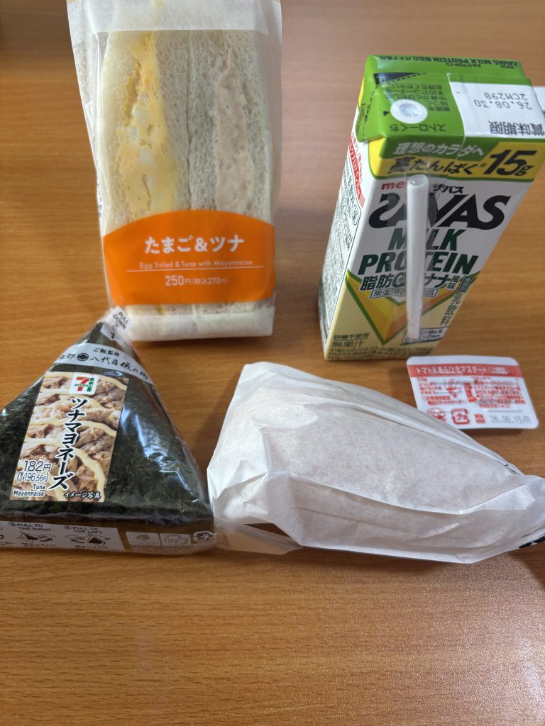 セブンイレブンのサンドイッチとザバスプロテインとツナマヨおにぎりと、ファミリーマートのアメリカンドッグ